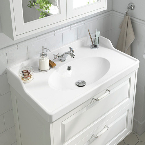 Un lavabo de baño impoluto con grifo cromado y dispensador de jabón, equipado con aireador ahorrador de agua.