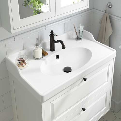 Lavabo de baño blanco con grifo y palanca negros, aireador, dispensador de jabón, porta cepillos de dientes.