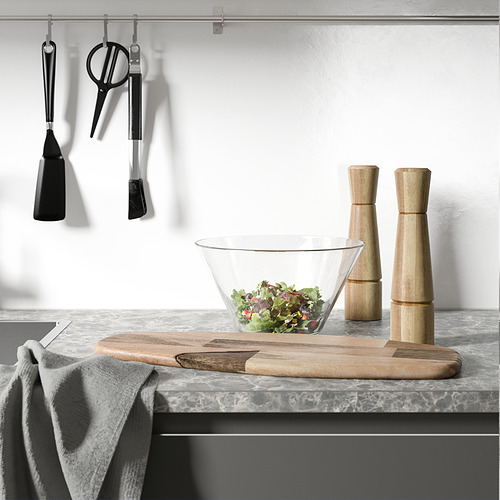 Encimera de cocina con ensaladera, molinillos de sal y pimienta, herramientas para colgar y una toalla.