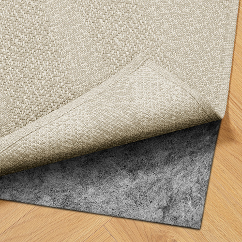 Una alfombra de color claro con alfombrilla antideslizante debajo, apta para uso en interiores o exteriores.