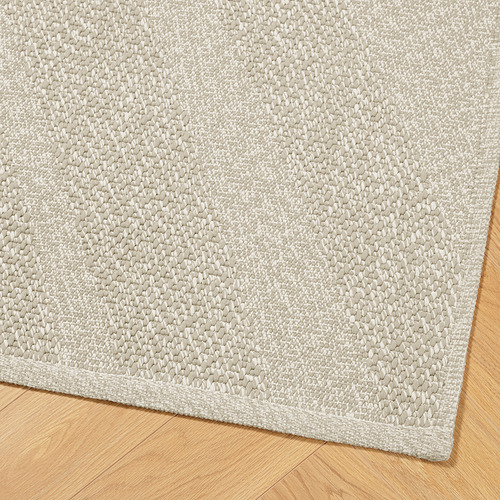 Alfombra de color gris claro con textura sobre suelo de madera, trama gruesa, cuidadosamente bordeada.