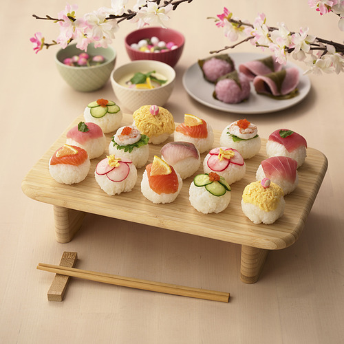 Tabla de sushi de madera con rollos y palillos de colores.