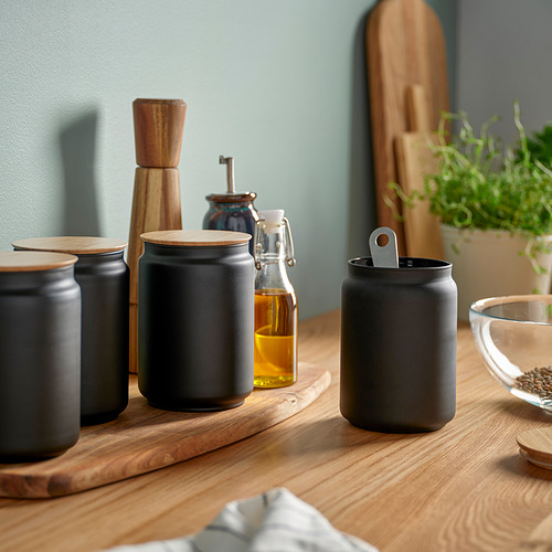 Moderno expositor de cocina con botes de cerámica negra, detalles en madera y botellas de vidrio en un estante de madera.