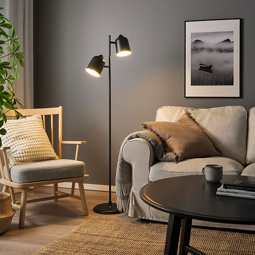 Sala de estar moderna con sofá gris, alfombra, lámpara de pie, silla, arte de pared, mesa de café y plantas.