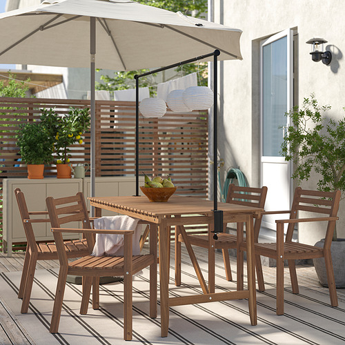 Conjunto de mesa de madera con 4 sillas a juego, listones, patas anguladas, sombreadas por sombrilla. Rodeado de decoración de cubierta.