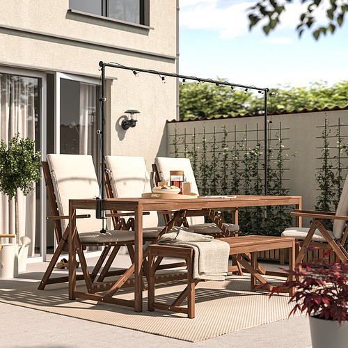 Patio trasero con juego de comedor NÄMMARÖ de madera oscura y luces colgantes. Cómodo para comidas al aire libre y relajación.