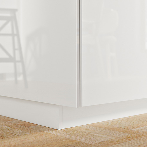 Zócalo de cocina blanco brillante contra suelo de madera.