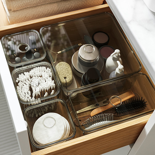 Cajón de baño organizado con contenedores VISSLAÅN: bastoncillos de algodón, accesorios para el cabello, maquillaje y cepillos ordenadamente en cajas transparentes.