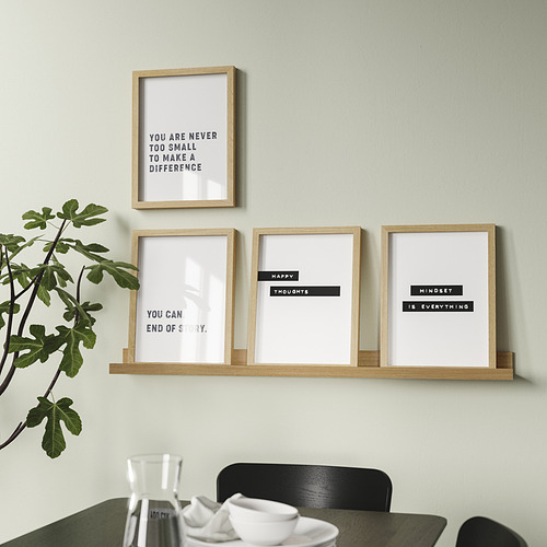 La moderna estantería montada en la pared muestra cuatro impresiones motivadoras enmarcadas y una planta en maceta, que brindan decoración e inspiración.