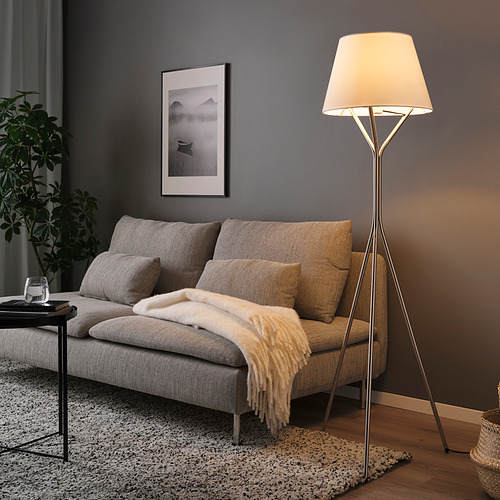 Sala de estar con lámpara BLÄNKFYR junto al sofá, luz cálida.