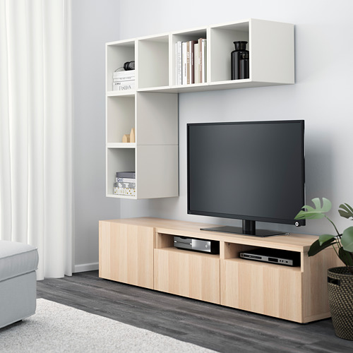 Sala de estar moderna con almacenamiento en la pared incorporado y mueble de TV de madera clara. El televisor de pantalla plana se encuentra en un soporte con estantes y cajones abiertos.