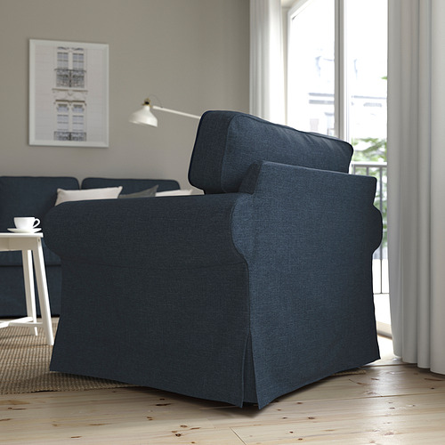 Sillón EKTORP gris oscuro junto a la ventana en un salón luminoso, cómodo y práctico con funda lavable.