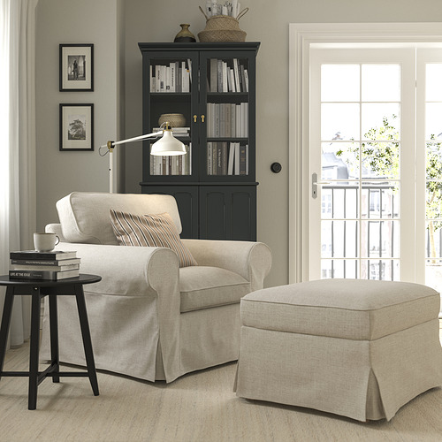 Acogedora sala de estar con muebles EKTORP beige, mesa auxiliar negra, estantería, lámpara y puerta de balcón.