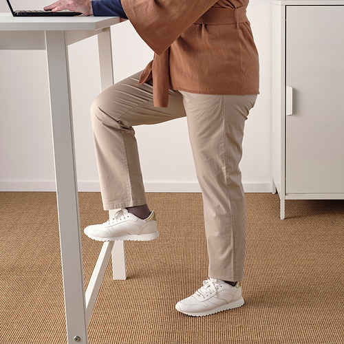De pie en el escritorio, rodilla en el reposapiés, computadora portátil. Espacio de trabajo ordenado para sentarse/estar de pie.