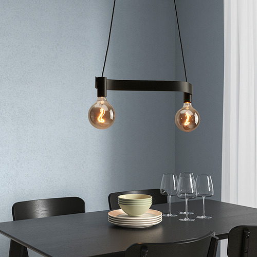 Lámpara ACKJA con dos bombillas sobre mesa oscura puesta con platos.