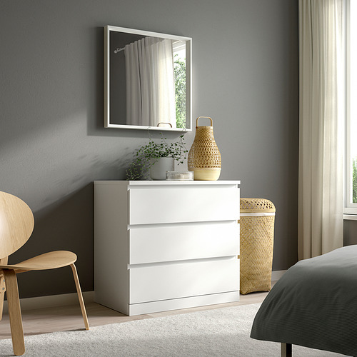Dormitorio minimalista con arcón, espejo, silla y cama NISSEDAL. Pared gris, suelo claro.