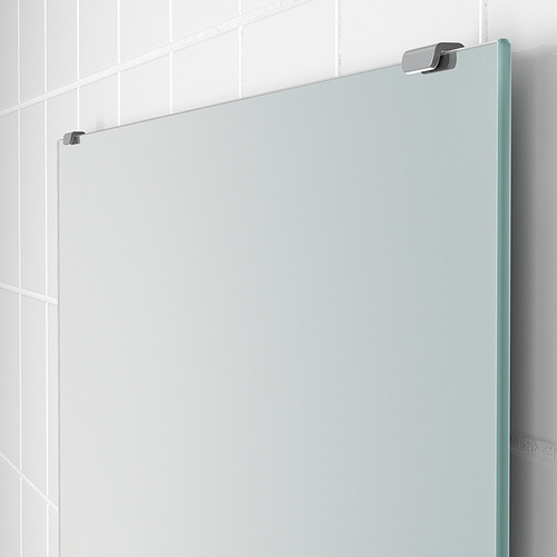 Moderno espejo sin bordes montado en una pared de azulejos blancos con elegantes accesorios de metal.