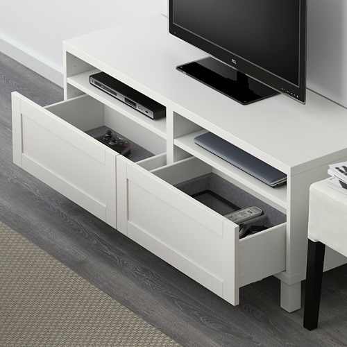 Mueble de tv blanco con cajones abiertos. Sostiene controladores de juegos, controles remotos y dispositivos electrónicos. Función de cierre suave y gestión de cables en la parte trasera.