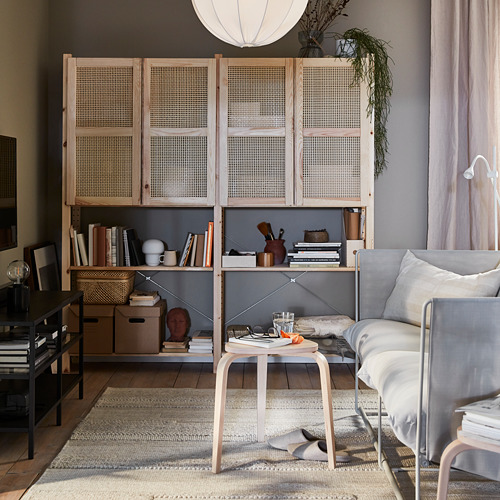 Sala de estar moderna con muebles de madera de colores claros, libros y plantas.