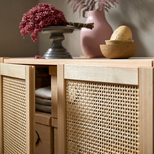 Gabinete IVAR con puertas de bambú tejido, color madera clara, estantes de almacenamiento y elementos decorativos en la parte superior.