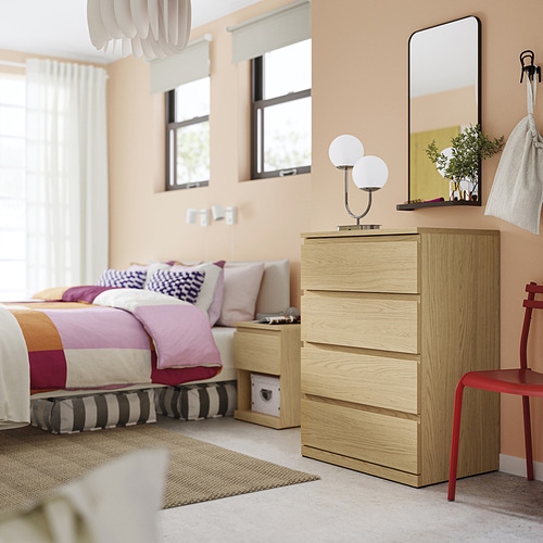 Dormitorio con arcón de madera clara, espejo, lámpara, silla roja. Alternativamente: dormitorio: arcón de madera clara, espejo, lámpara, silla roja, ropa de cama colorida.