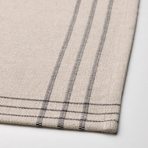 Mantel individual de rayas beige, tejido en algodón y yute, sobre una superficie blanca.