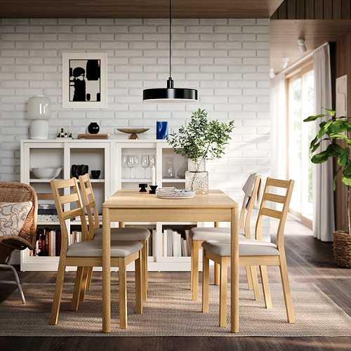Comedor moderno con mesa de roble, sillas, puertas de patio, plantas, arte, luz colgante y grandes ventanales.