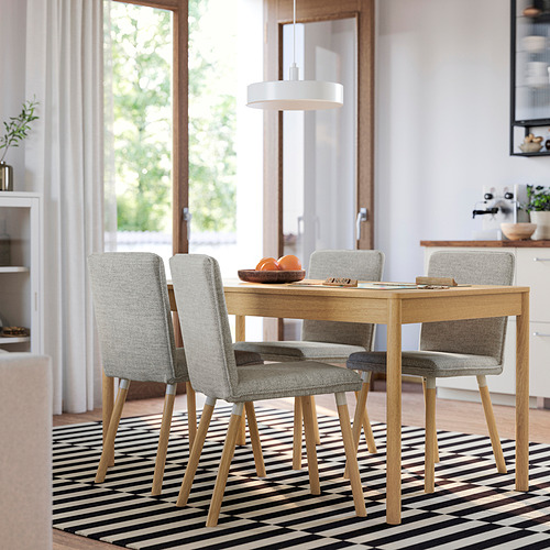 Mesa de comedor de madera con sillas, alfombra blanca/negra, naranjas.