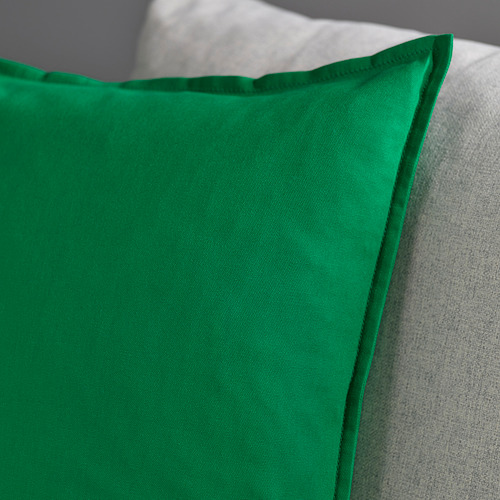 Un primer plano de una funda de cojín verde con detalles de costuras visibles, que muestra su textura y calidad.