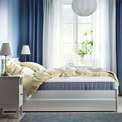Dormitorio con colchón VESTERÖY, ropa de cama azul claro, lámparas en mesitas de noche, gran ventana con cortinas transparentes, lámpara colgante y alfombra.