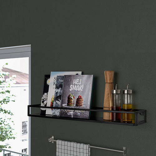 Estante de pared negro que contiene libros de cocina, especias y un molinillo de pimienta de madera cerca de una ventana.