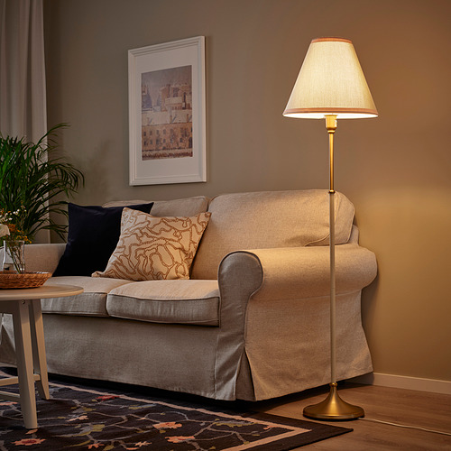 Sala de estar moderna con lámpara FLYGHÖJD, sofá beige, planta y arte de pared.