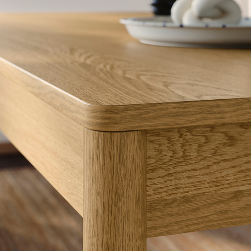 Primer plano de la mesa de comedor de madera natural. Bordes suaves y redondeados y ricos patrones de grano. Las robustas patas soportan un acabado mate cepillado.