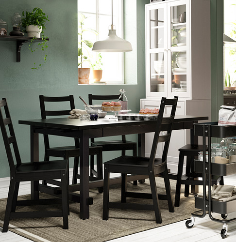 Acogedora zona de comedor con sillas NORDVIKEN negras alrededor de una mesa rectangular, decorada con paredes verde azulado y armarios blancos.