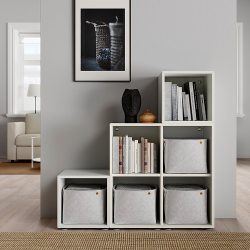 Moderna estantería de cubo blanco con contenedores grises, artículos decorativos y libros; Arte minimalista sobre pared gris.