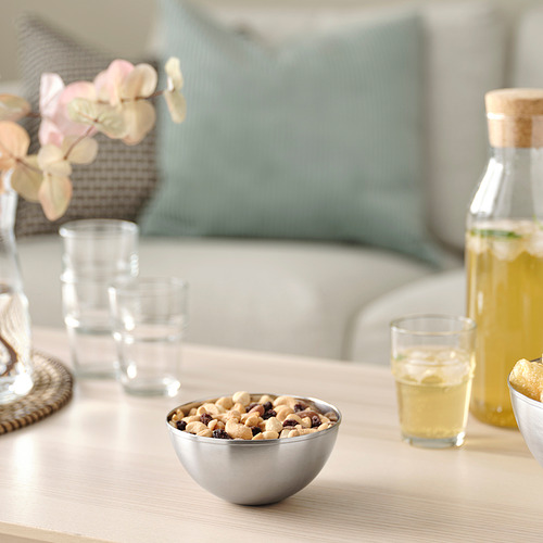 Cuenco de acero inoxidable con frutos secos sobre la mesa, rodeado de vasos y limonada.