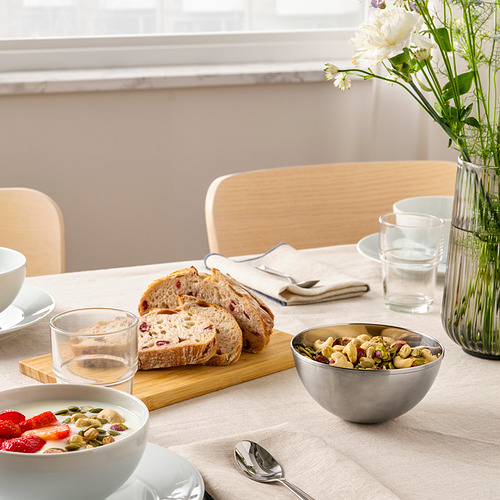 Mesa de desayuno con cereales, pan, nueces y flores.