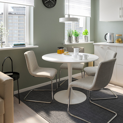 Cocina moderna con mesa DOCKSTA, sillas acolchadas, tetera, tazas y jarrón cerca de ventanas con luz natural y paredes verdes.