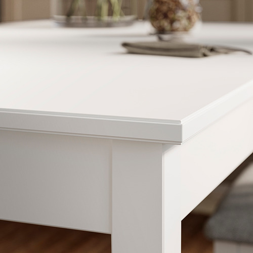 Primer plano de las mesas NÄSINGE elegante, borde blanco; Tapa de melamina lisa, pata de madera resistente y diseño limpio.