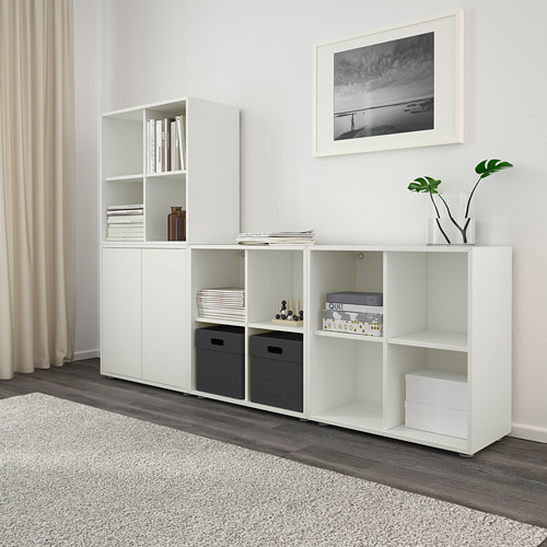 Modular storage with open/closed compartments, shelves with books, decor, and plants. Beach photo on wall.