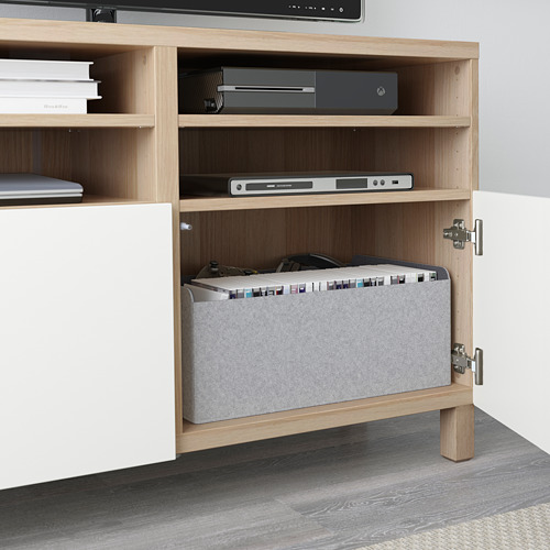 Un mueble de televisión de madera con estantes abiertos, que alberga dispositivos electrónicos y una computadora portátil.