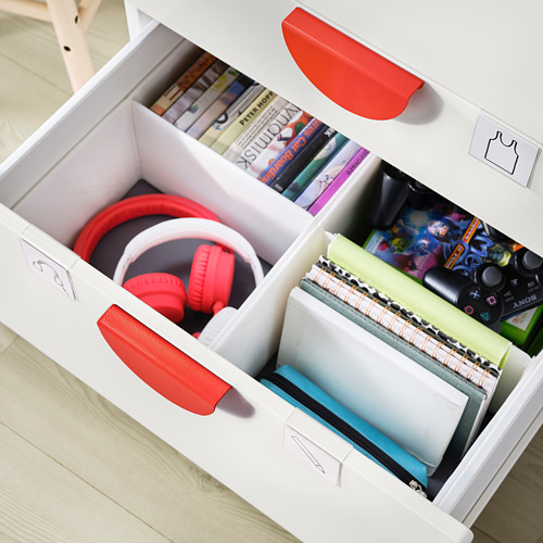 Unidad de almacenamiento blanca con manijas rojas que contiene artículos como auriculares, cuadernos y controladores de juegos rojos.