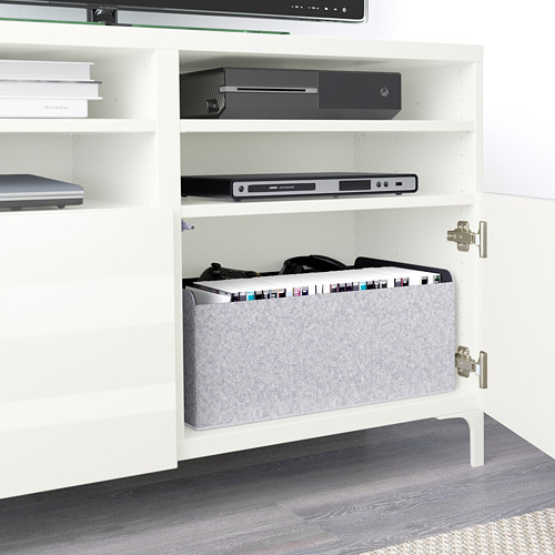 Mueble de televisión blanco BESTÅ con estantes para almacenar productos electrónicos, incluido un reproductor de DVD y una consola de juegos. Las puertas de cierre suave ocultan los cables multimedia organizados.
