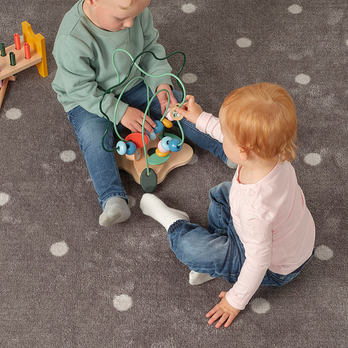 Dos niños juegan con un laberinto de cuentas, aprendiendo formas y colores.