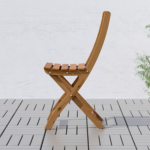 Silla plegable de madera sobre baldosas grises, mostrada de lado. Ideal para espacios pequeños, madera de acacia duradera.