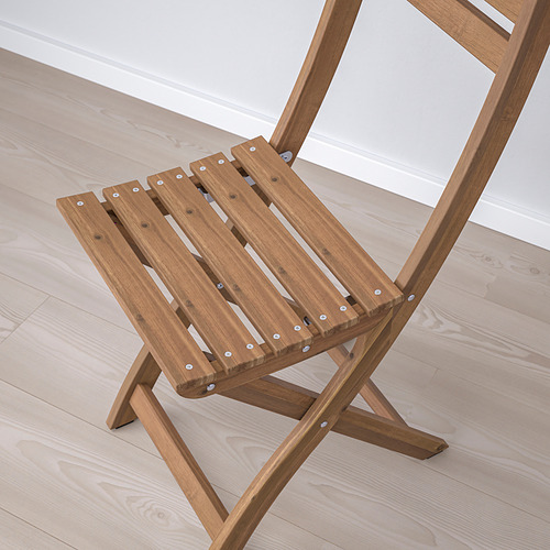 Silla plegable de madera sobre suelo de madera clara, elaborada con madera de acacia duradera, vista desde arriba.