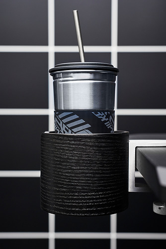 Portatazas de metal negro sujetado a un escritorio con una taza de plata en su interior.