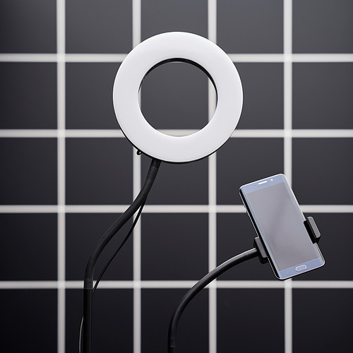 Dispositivo LÅNESPELARE: anillo de luz blanco, soporte de teléfono negro, brazo flexible, fondo de mosaico cuadrado.