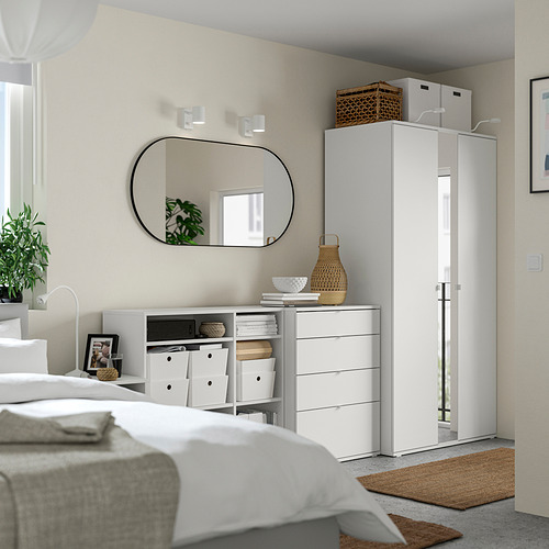 Moderno dormitorio blanco con armario, arcón, espejo y decoración natural. Diseño limpio y minimalista.