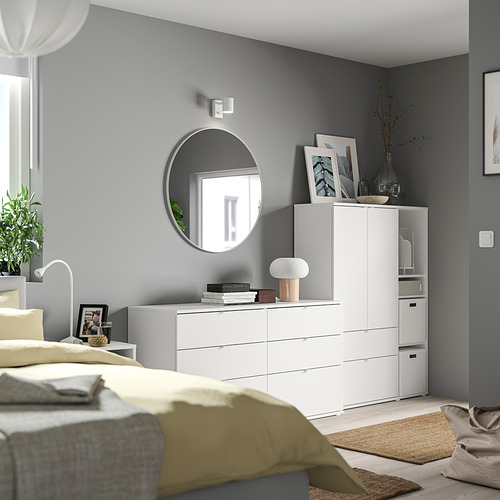 Dormitorio moderno con paredes grises, muebles blancos, manta amarilla, espejo redondo, lámpara y elementos decorativos.